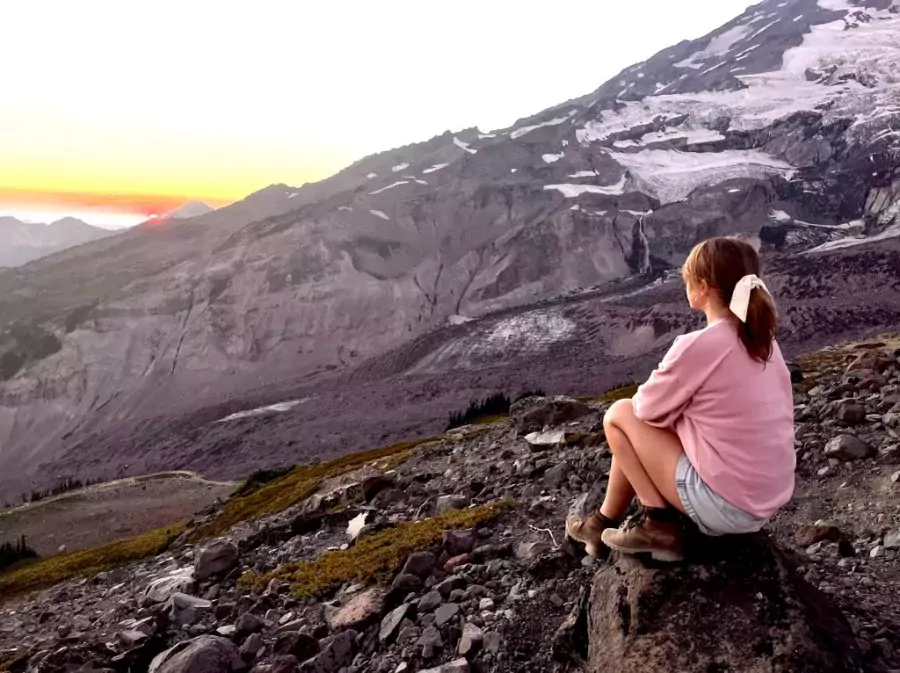 Woman sitting by a mountain looking on the view during a hike contemplating how to become a more effective person.